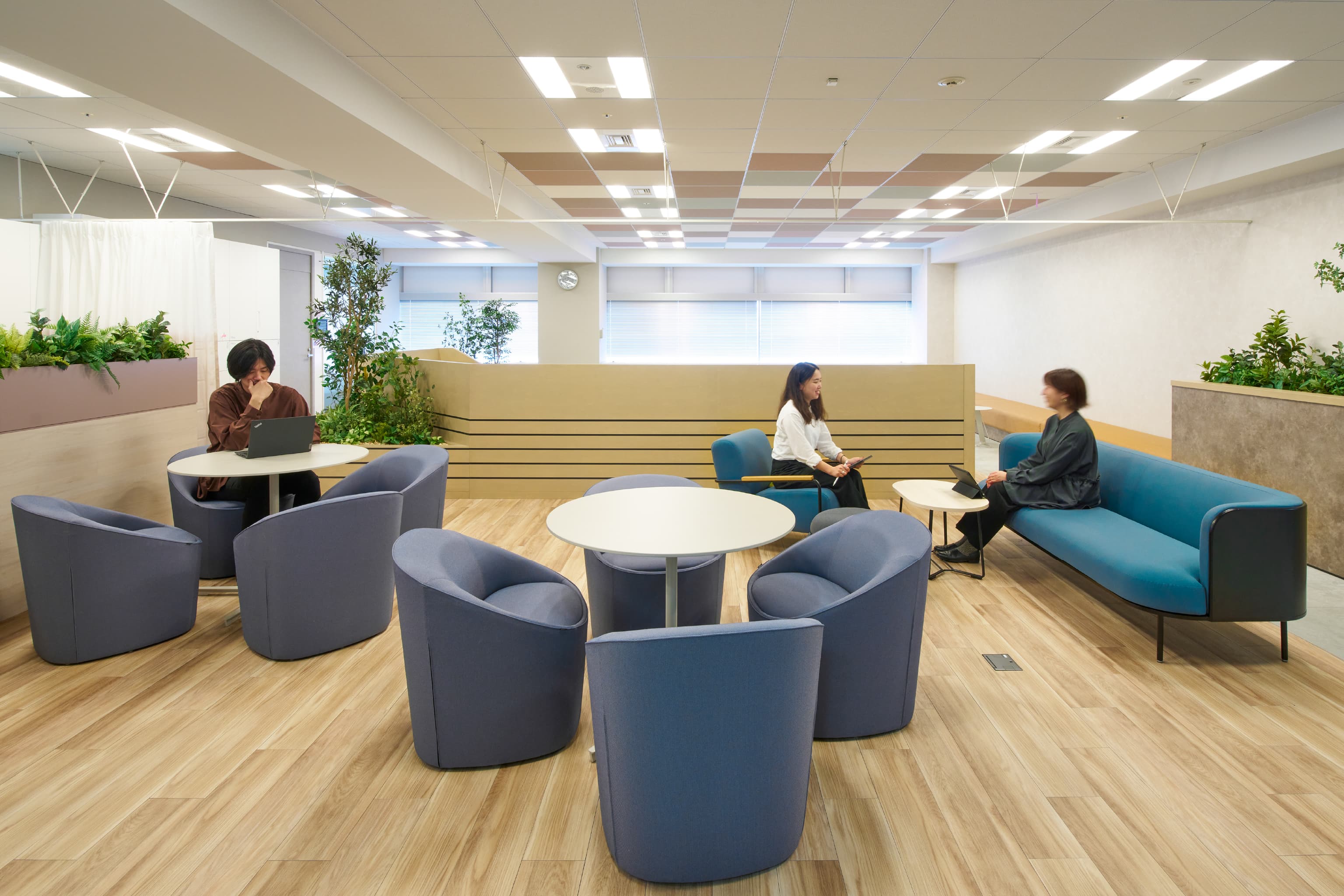 IQVIA ジャパン グループ 様の事例写真／[共創空間（8階STAGEエリア）]ステップベンチの裏側には、開け閉め可能なカーテンで仕切ったソファエリアがあります。共創空間で話し合ったことをまとめる、ラップアップの場所として利用できる空間です。